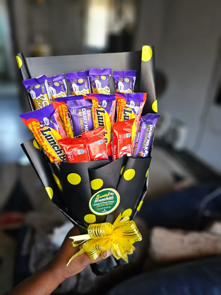 Chocolate bouquet wrapped in black polka-dot paper with a yellow ribbon bow, held in hand